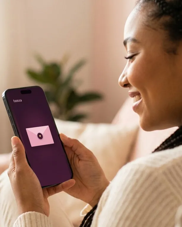 A woman smiling at a Tunza gift envelope on her phone